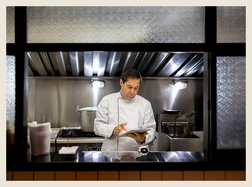 Chef reading a clipboard in kitchen.